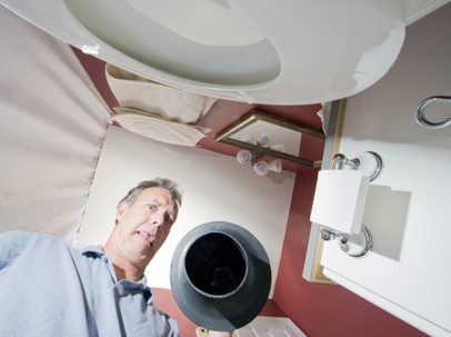 man holding plunger looking down into toilet